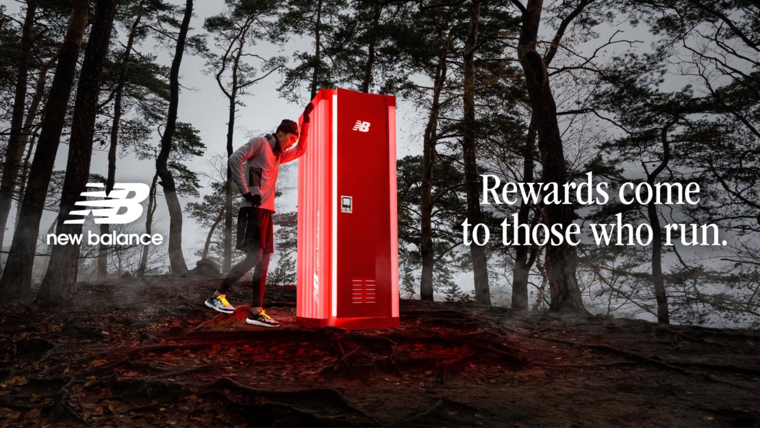 An athletic man pauses by a red New Balance branded locker on a forest trail with the tagline 'Rewards come to those who run'.