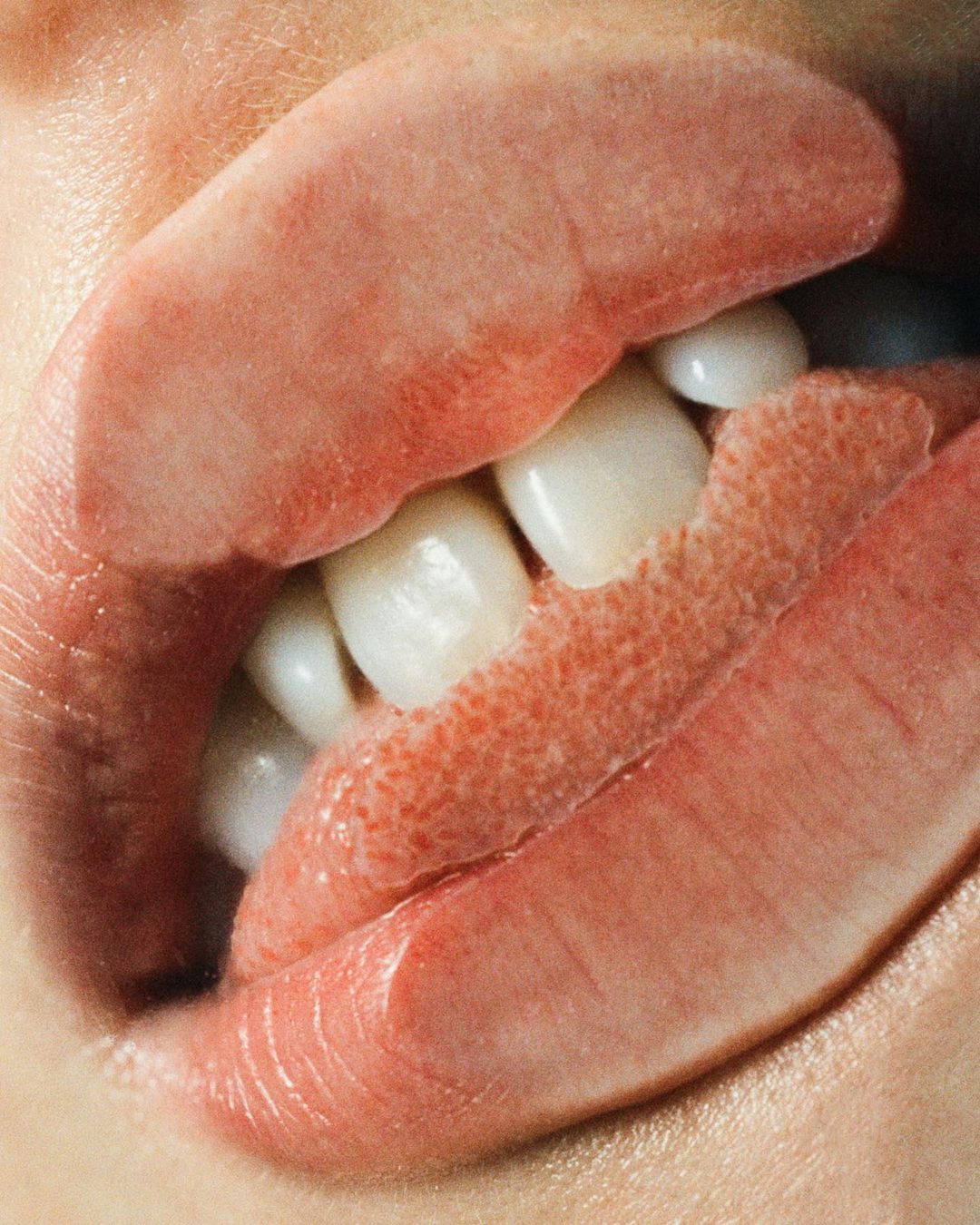 Macro shot of an open mouth revealing white teeth and a tongue, showcasing dental detail in a close-up, intimate perspective.