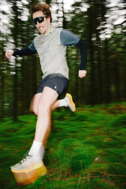 Adult male runner in sunglasses and athletic wear running through a forest in motion blur, showcasing active lifestyle and outdoor fitness.