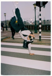 Man upside down performing a handstand on a pedestrian crossing street with lanterns in background