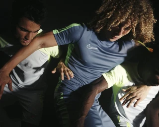 Three athletic male models in grey and lime sports apparel interlocking arms in a dynamic athletic shoot by Elliott Wilcox.