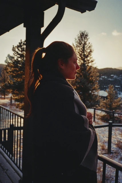 A portrait showcases a woman with brown hair, wearing a gray turtleneck sweater, in soft lighting against a muted background.