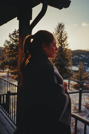 A portrait showcases a woman with brown hair, wearing a gray turtleneck sweater, in soft lighting against a muted background.
