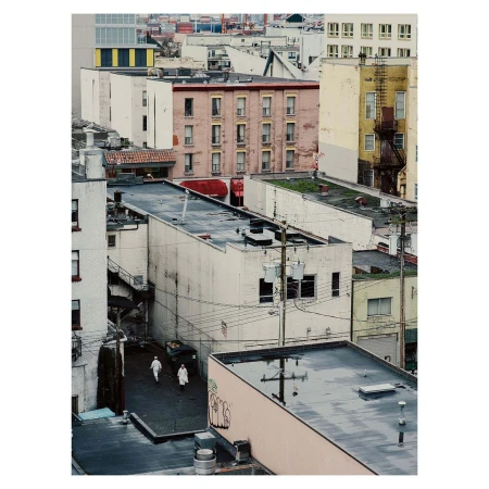 Urban cityscape featuring apartment buildings, city street, and two people walking; neutral, muted tones, aerial view.