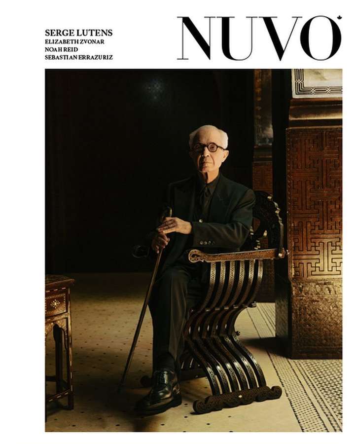 Magazine cover featuring an older man in a suit seated indoors in an ornate chair, holding a cane, with dark and patterned background.