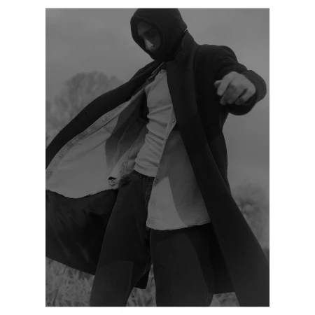 Man wearing a dark hooded coat, light t-shirt, and dark pants outdoors by Grant Harder