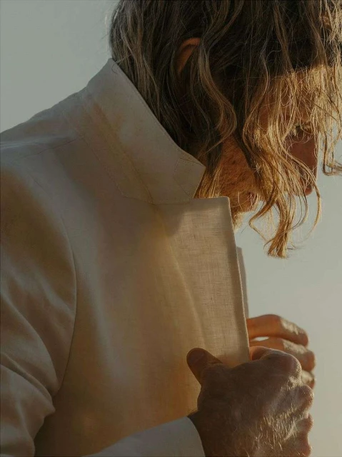 Close-up of a person in a white linen blazer, showcasing the fabric's texture and the soft, diffused light, with a minimalist aesthetic.