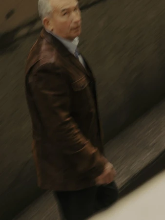 An older man in a brown leather jacket and collared shirt walking in Vancouver, captured by Grant Harder.