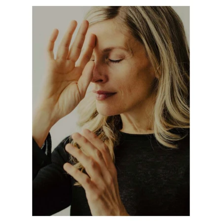 Portrait of a blonde woman in a black top with her hand raised near her forehead, photographed by Grant Harder