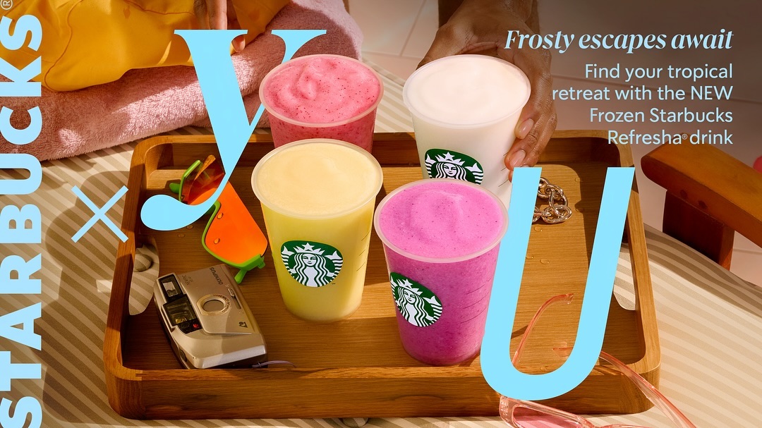 Four Starbucks frozen drinks on a wooden tray with sunglasses, vintage camera, and beach towel in the background. Summer themed.