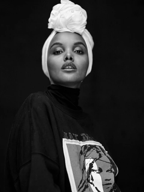 Striking black and white portrait of an adult female with white headscarf, looking at the camera wearing a graphic shirt.