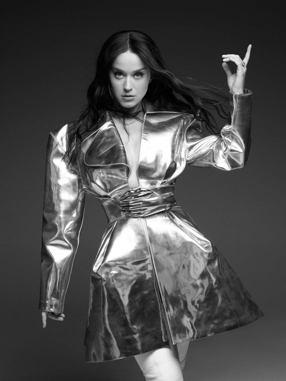 Black and white portrait of an adult woman wearing a shiny, futuristic-looking jacket, standing in front of a dark background.