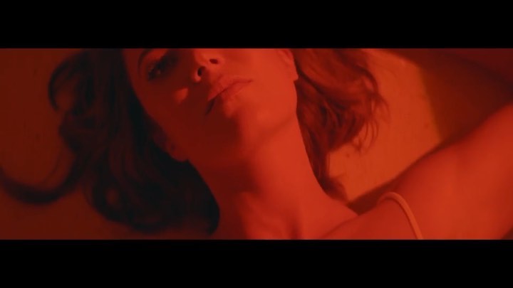Close-up portrait of a woman lying down under dramatic red lighting by photographer Lauren Dukoff.
