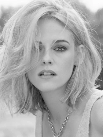 Black and white portrait of actress Kristen Stewart with blonde hair and dark eye makeup wearing a chain necklace