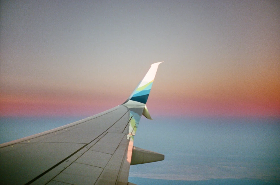 Airplane wing during flight with the sky and horizon visible in the background, shot from inside the aircraft, travel concept, aerial view.