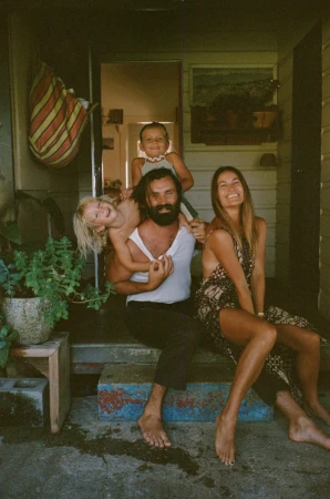 Family sitting together on a porch by Magdalena Wosinska, featuring a man, a woman, and two children.
