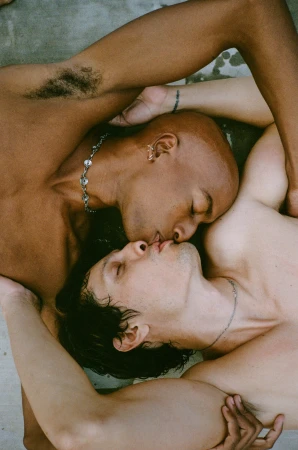 Two shirtless men embracing and kissing closely from an overhead angle, captured by photographer Magdalena Wosinska.
