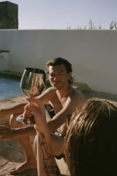 Man seated by a pool holding a metal wine glass, photographed by Magdalena Wosinska