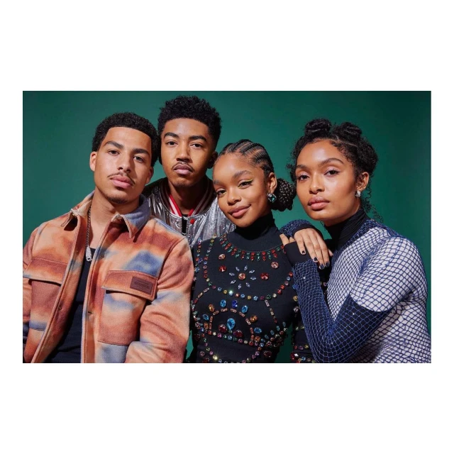 A group of four stylish African-American young adults pose indoors against a dark green backdrop, showcasing modern fashion and hairstyles.