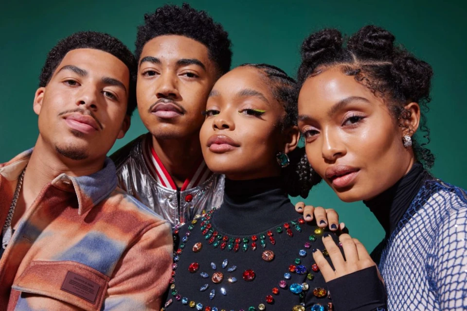 Four young adult models pose together indoors against a solid green backdrop, showcasing modern fashion and beauty styles.