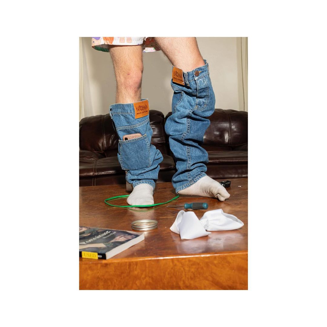 Person posing with denim leg warmers on a wooden surface, showcasing fashion and style in an indoor setting with visible props.