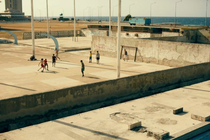 Youth soccer game on a concrete pitch by the sea under a clear sky, showcasing an active lifestyle in an urban coastal environment.