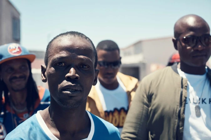 Close-up of a group of African men outdoors. One man is in focus in the foreground with others behind him on a city street.