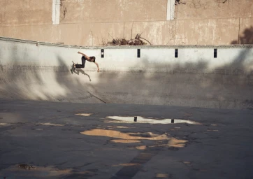 Skater carving the curved wall of an empty concrete swimming pool, photographed in natural sunlight by Olly Burn.