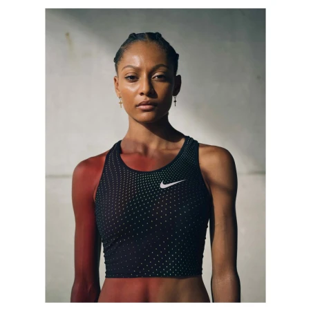 Portrait of an athletic woman wearing a black Nike sports bra with a serious expression, photographed in a photo studio with diffused lighting.