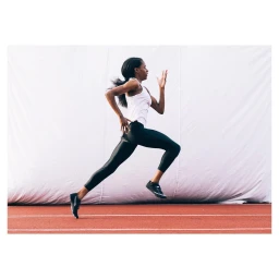 Black female athlete running on a track against a white backdrop photographed by Paul Calver