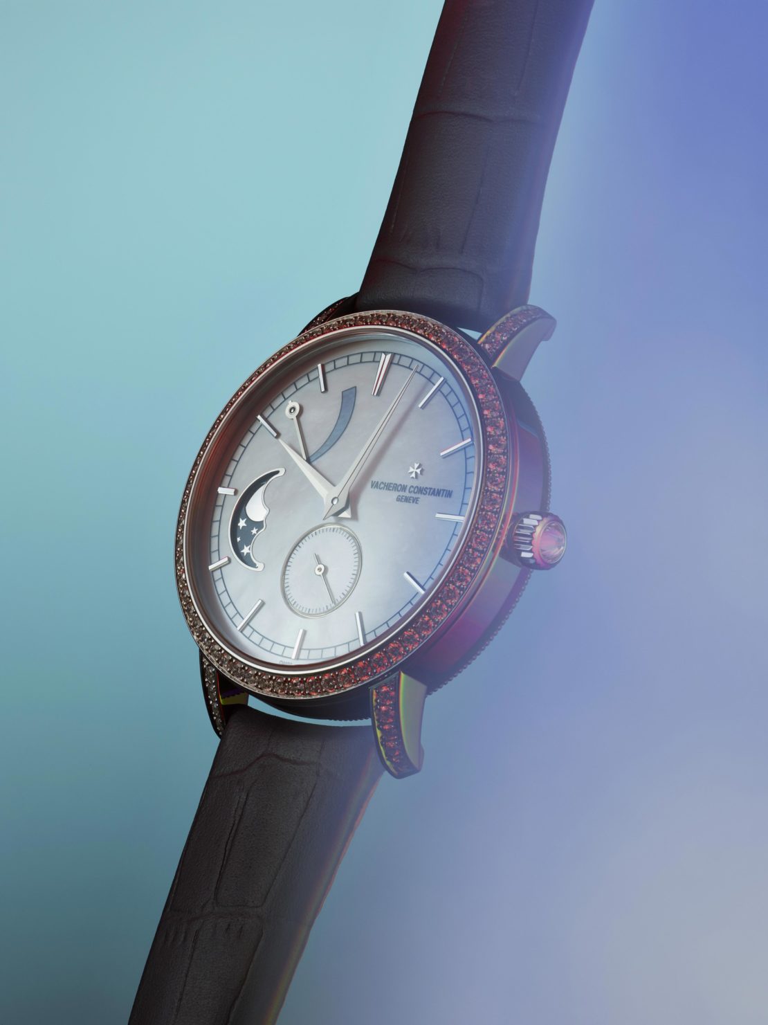 Wristwatch close-up featuring a silver face with a moon phase dial, surrounded by gems, paired with a brown leather band.