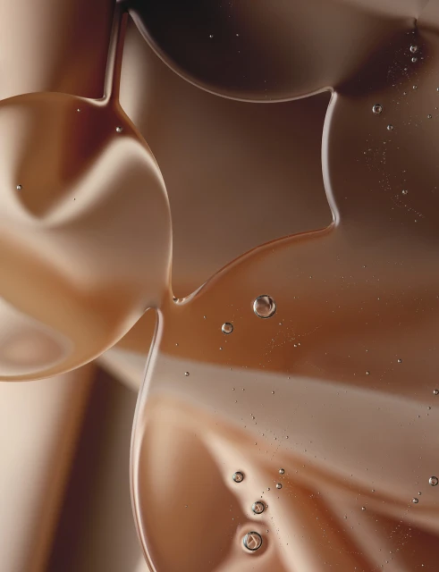 Abstract close-up of viscous liquid with suspended bubbles, featuring warm brown and tan tones, creating a smooth, flowing texture.