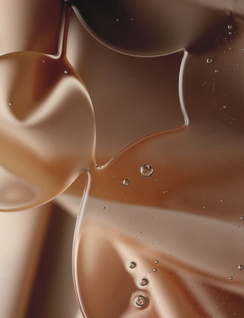 Abstract close-up of viscous liquid with suspended bubbles, featuring warm brown and tan tones, creating a smooth, flowing texture.