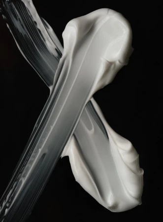 Close-up of thick smears of white cream against a stark black background creates a minimalistic and textural beauty or skincare visual.