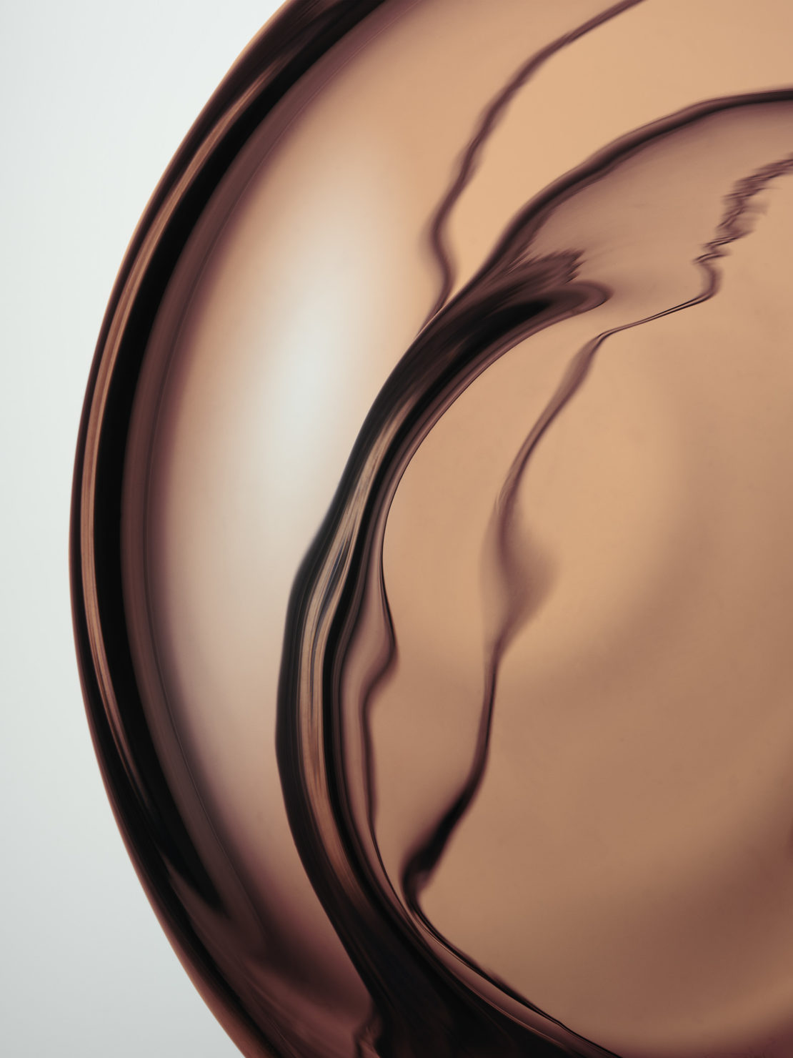 Abstract studio shot of reflective copper metal surface showcasing curved lines, and unique light play in an artistic composition.