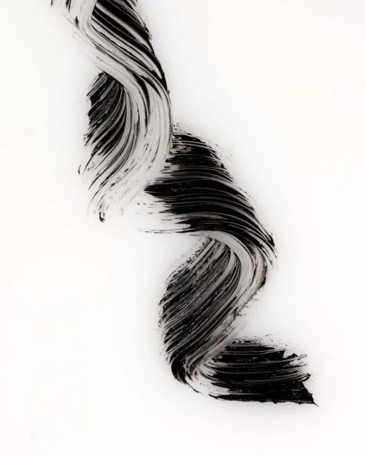 Textural abstract image of a swooping wave-like pattern of black mascara against a stark white backdrop, beauty product advertisement.