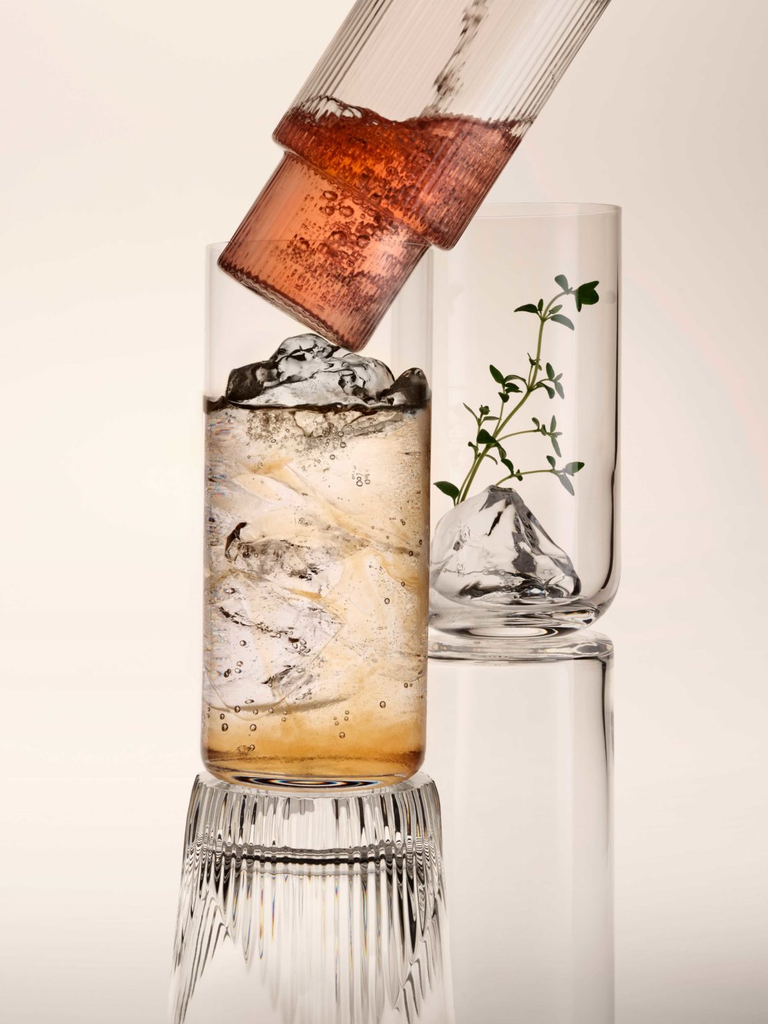 Still life shot of beverage in clear drinking glasses with decorative ice or glass formations, neutral background in a studio setting.