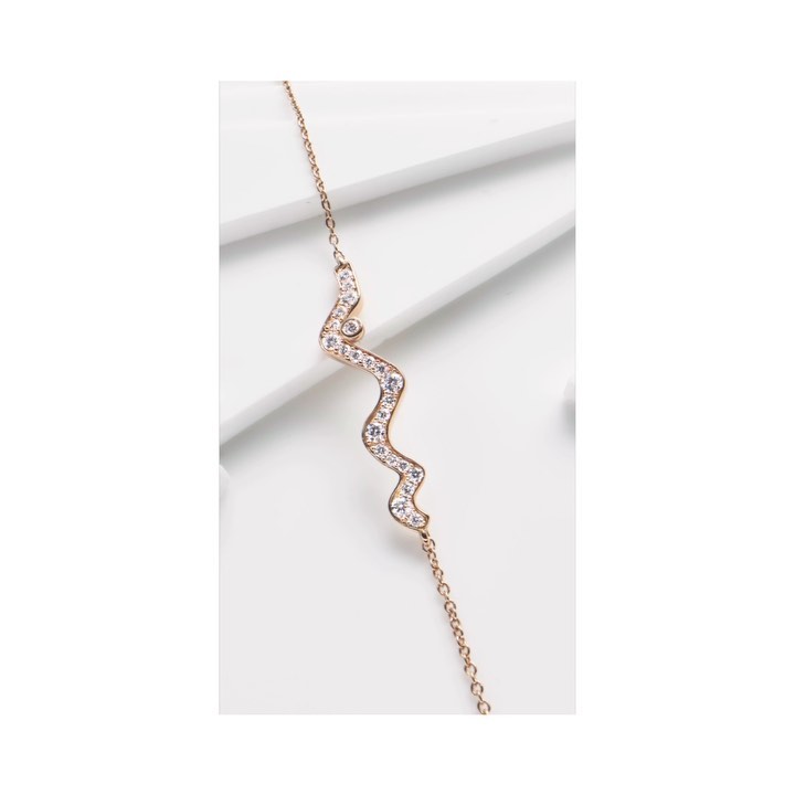 Close-up studio shot of a delicate rose gold chain necklace with crystal embellishments on a clean white surface and soft lighting.