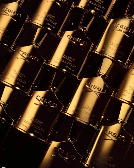 Multiple Creed Millesime Imperial perfume bottles arranged closely together, featuring gold accents and dark background. Luxury fragrance concept.
