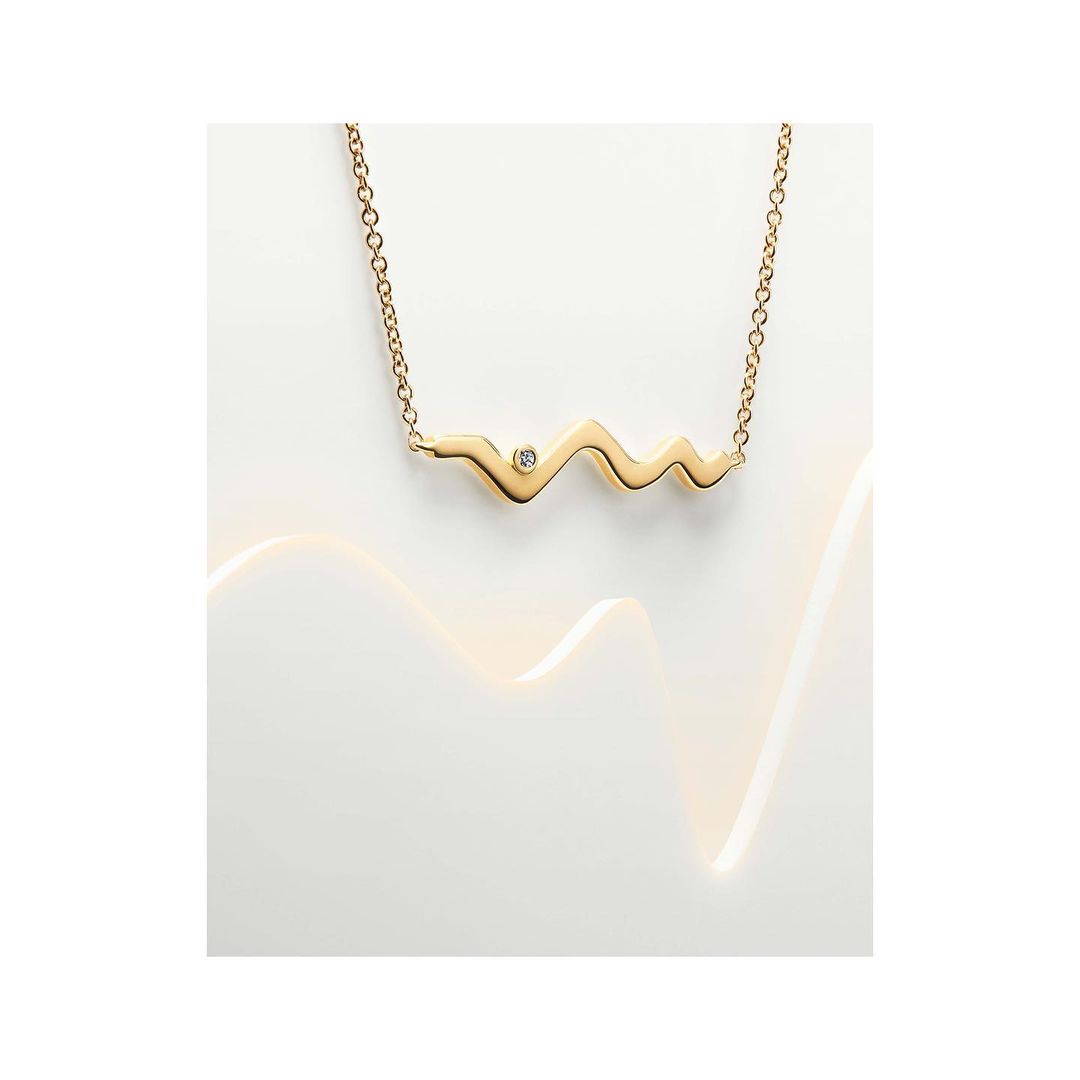 Elegant gold pendant necklace with a delicate chain and gemstone, beautifully illuminated against a soft, neutral backdrop.