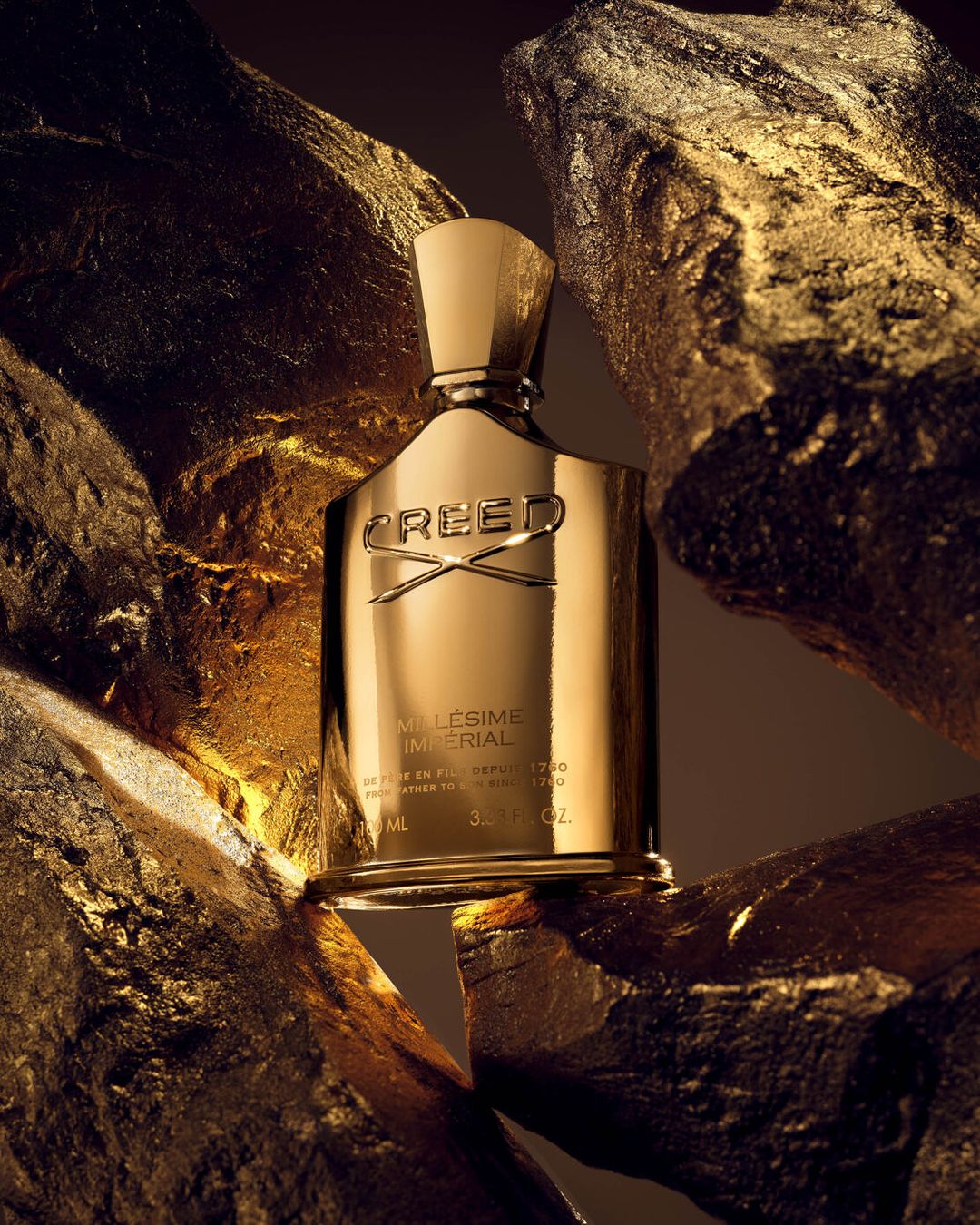 Elegant gold perfume bottle by Creed surrounded by gold rocks, studio product shot for fragrance and beauty advertising, luxurious aesthetic.