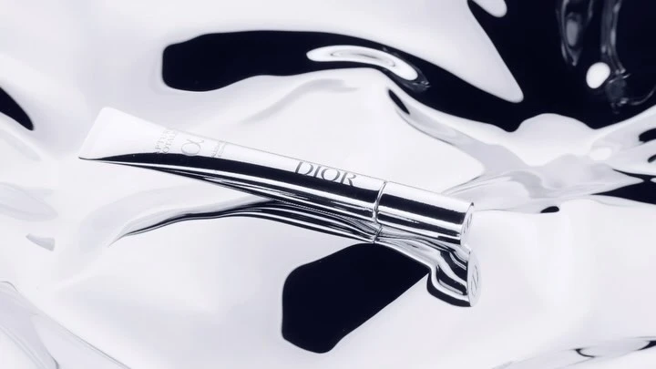 Dior skincare product tube on a reflective black and white surface, product shot for the beauty industry, luxury packaging.