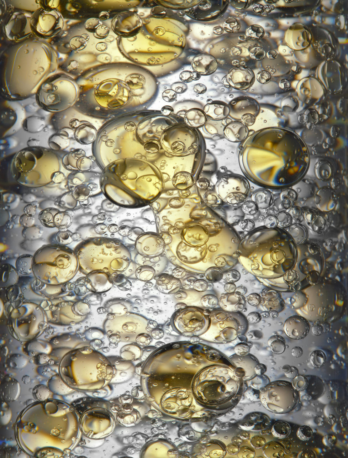 Close-up shot featuring a mesmerizing collection of clear and golden liquid bubbles floating together, creating an abstract liquid motion.
