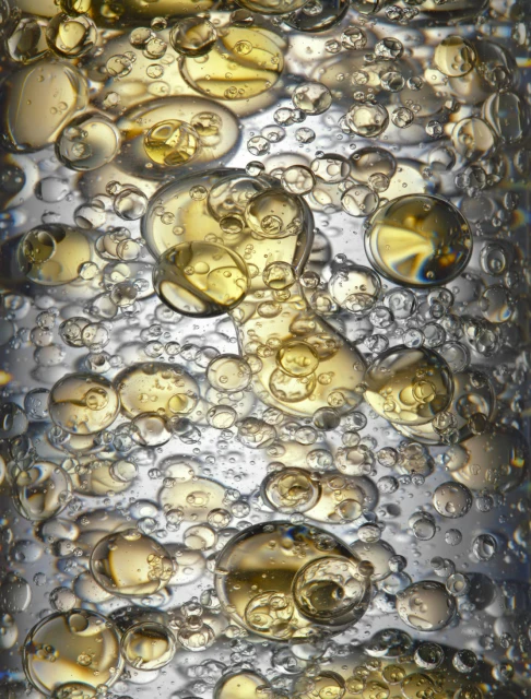 Close-up shot featuring a mesmerizing collection of clear and golden liquid bubbles floating together, creating an abstract liquid motion.