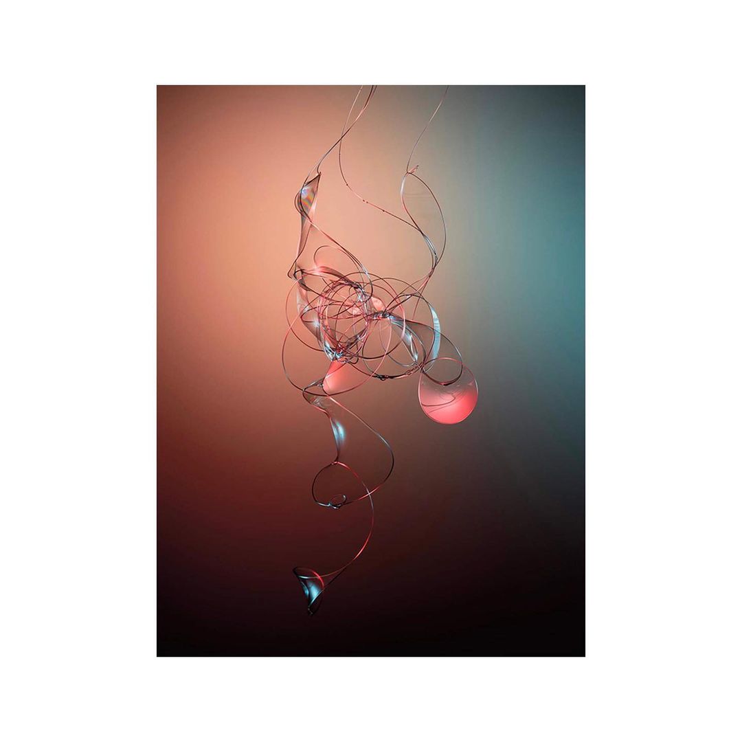 Delicate intertwining glass filaments and spheres suspended against a gradient warm peach and teal backdrop.