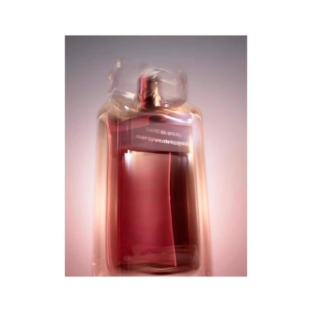 Abstract studio shot of a translucent glass perfume bottle with a pink hue, featuring blurred motion and a clean, minimalist aesthetic.