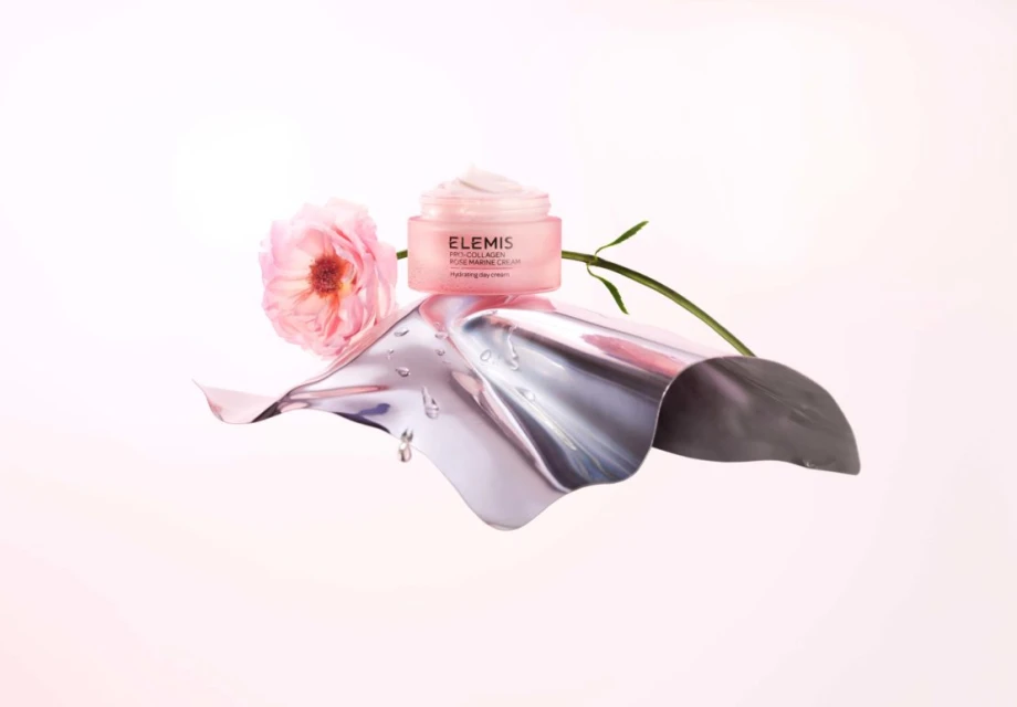 Product shot of Elemis Pro-Collagen Rose Marine Cream on a metallic surface with a pink rose against a gradient pink backdrop.