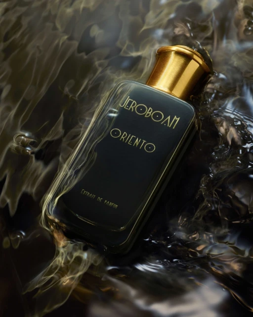 Close-up studio shot of a perfume bottle with a gold cap partially submerged in swirling black water. Cosmetic product for fragrance.