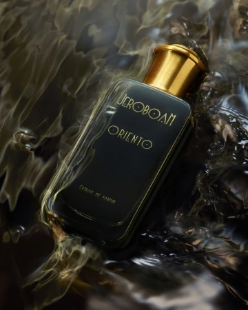 Close-up studio shot of a perfume bottle with a gold cap partially submerged in swirling black water. Cosmetic product for fragrance.