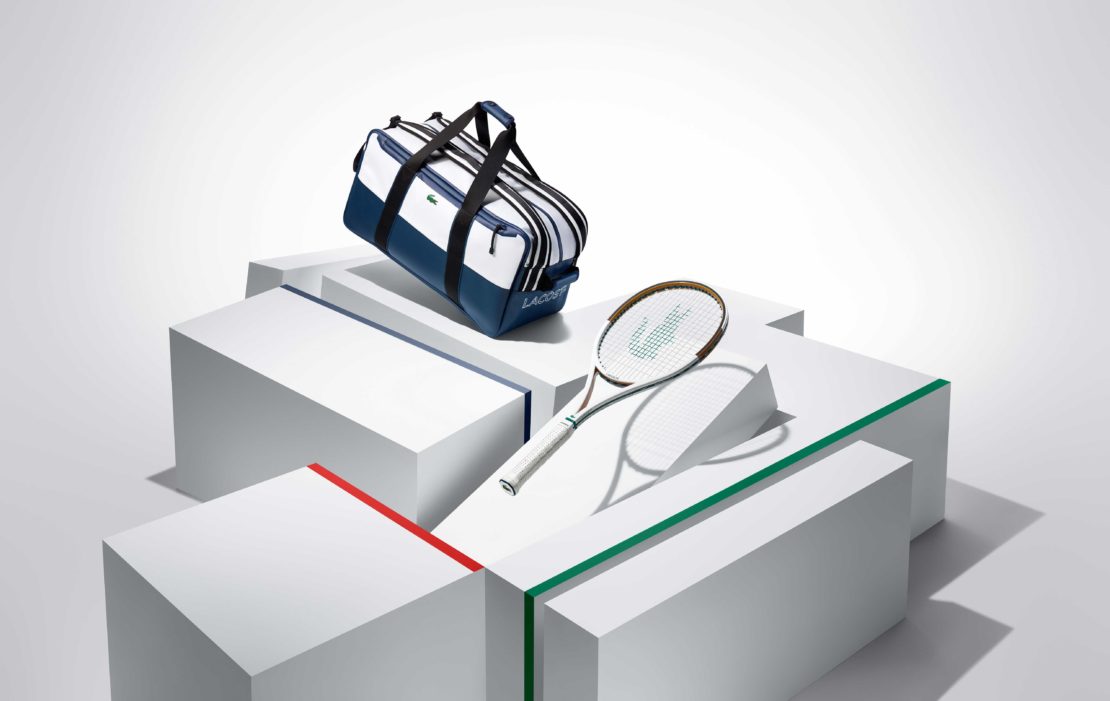Lacoste tennis bag and racket on white geometric platforms, product shot for advertising, clean modern style, blue, white, green and red.